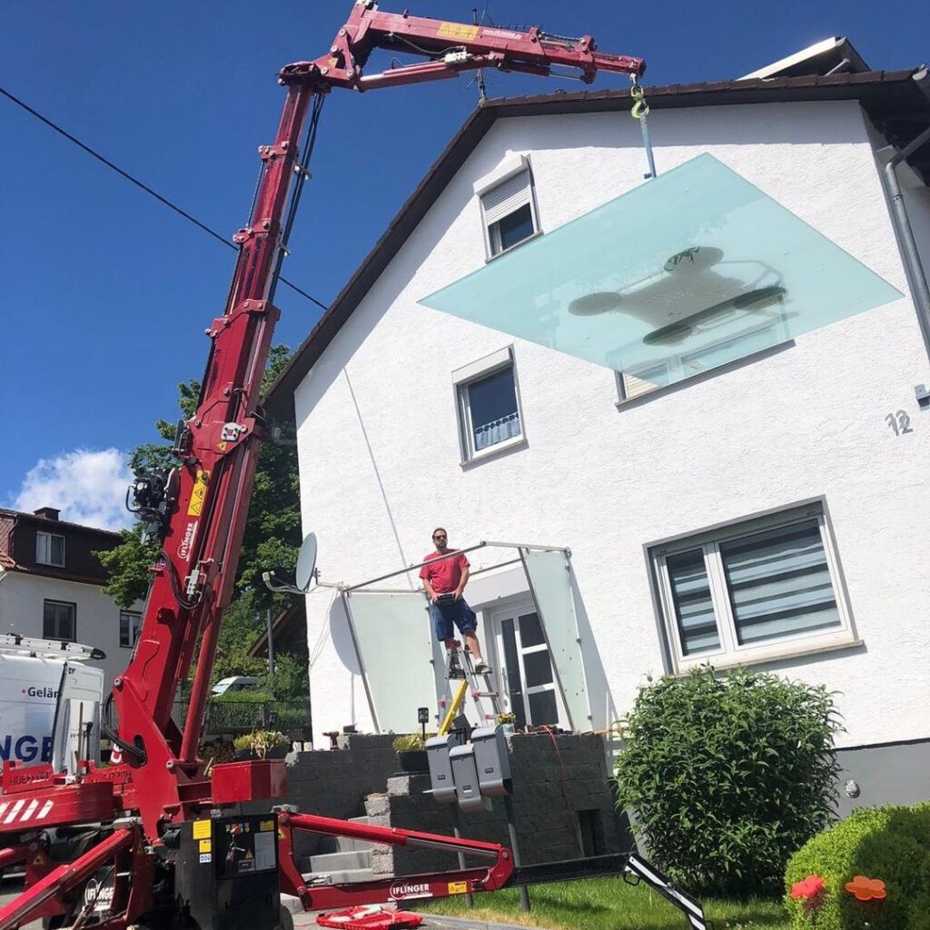 Die Vordachscheibe wird mit dem Minikran an seinen Platz gehoben